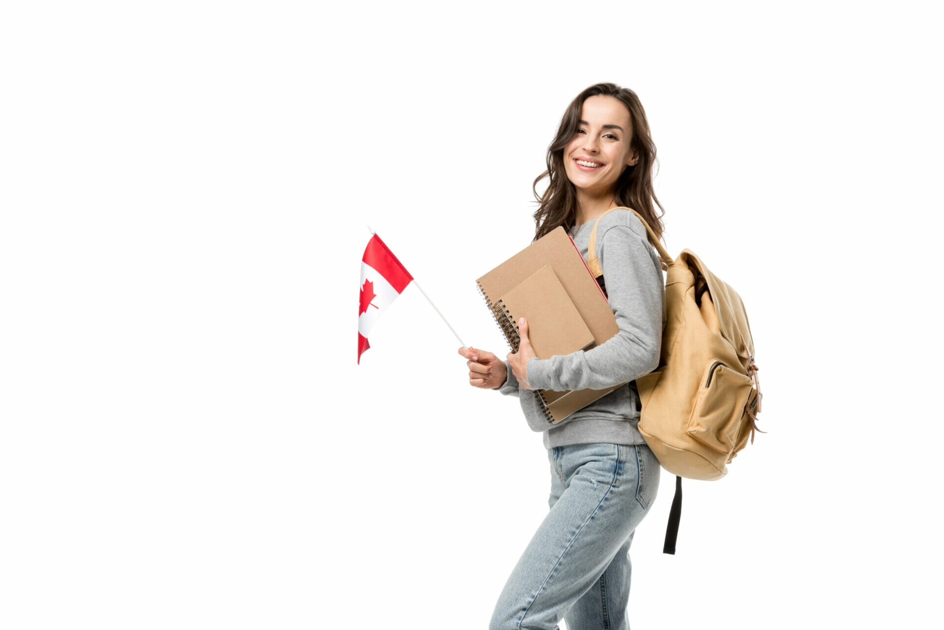 happy female student with backpack and notebooks looking at camera while holding canadian flag